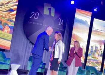 Neli Ulrich, PhD, MD, shakes hands with Gov. Spencer Cox while receiving her award at the One Utah Summit