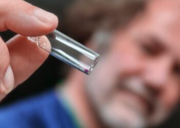 Scientist holds a vial with a glass bead