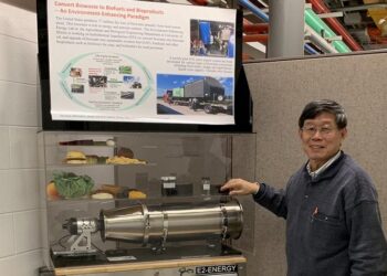 A man stands next to a display with a poster and a reactor model.